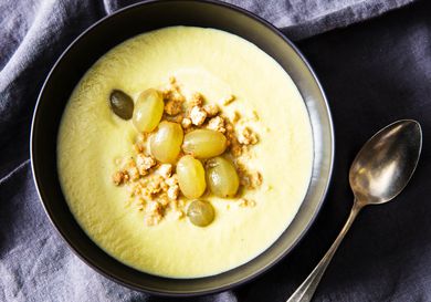 Overhead view of celery soup, topped with pickled grapes and peanut crumble.