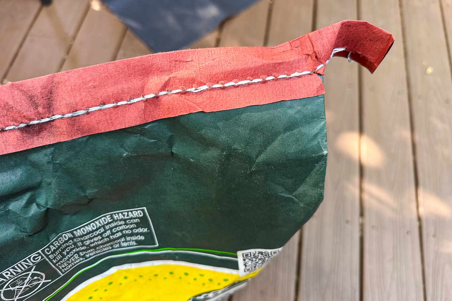 A closeup of a bags stitched top edge with text and warning label visible