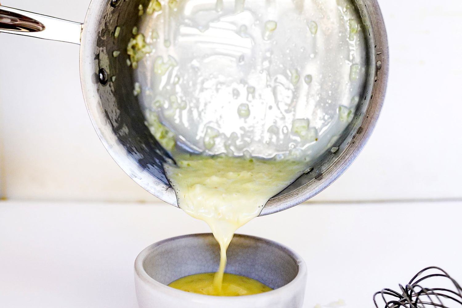 Food being poured out of a pot from the All-Clad D3 3-Ply Stainless Steel Cookware Set 10 Piece