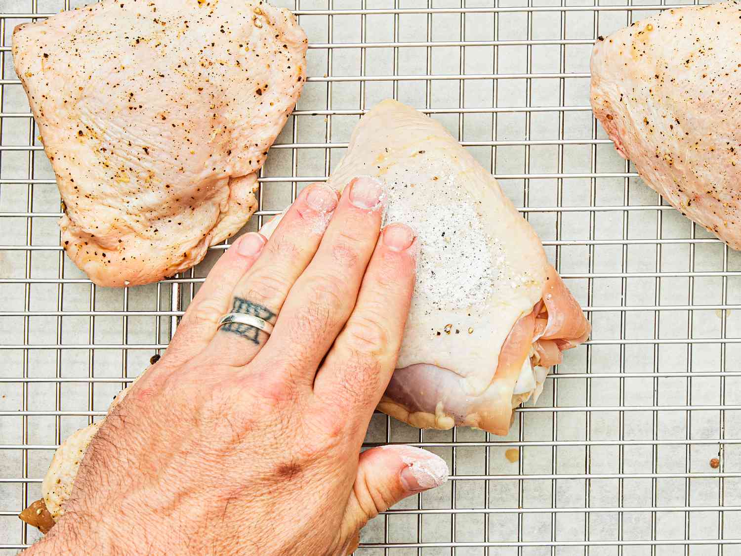 Patting chicken thighs with a dry brine