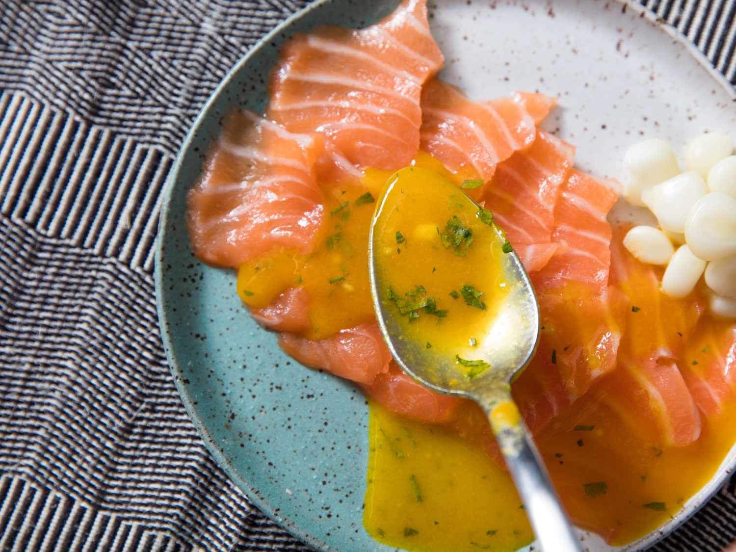 Spooning sauce onto salmon tiradito.