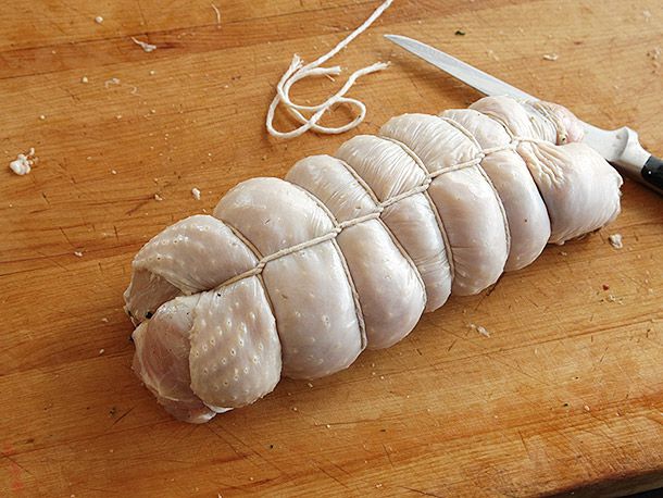 Trussed up raw turkey porchetta on cutting board