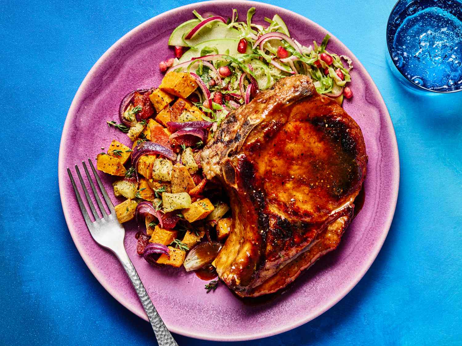 Dish with a glazed pork chop roasted vegetables and a fresh salad on a plate