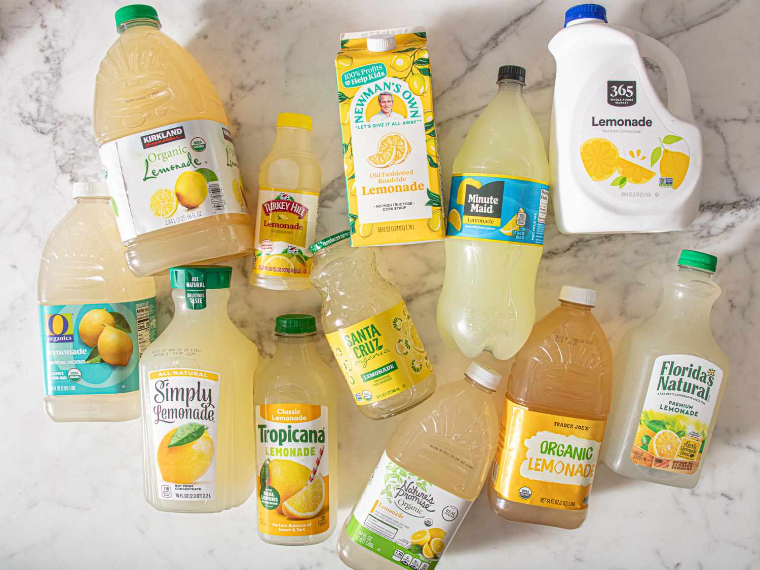 A variety of lemonade brands arranged showing different bottles and cartons on a marble surface