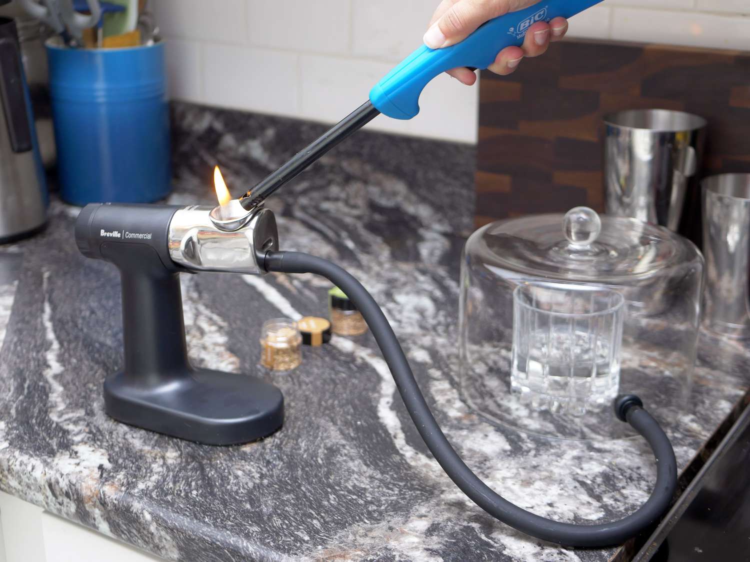 a hand lighting the breville polyscience smoker with a lighter