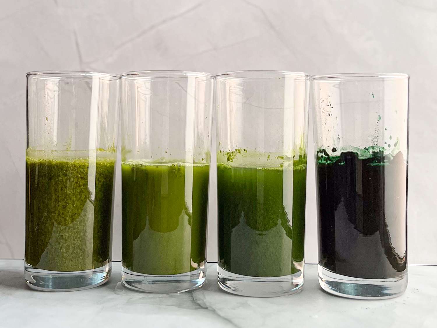 Glasses of water with dissolved pandan powder, matcha, spinach powder, and spirulina powder