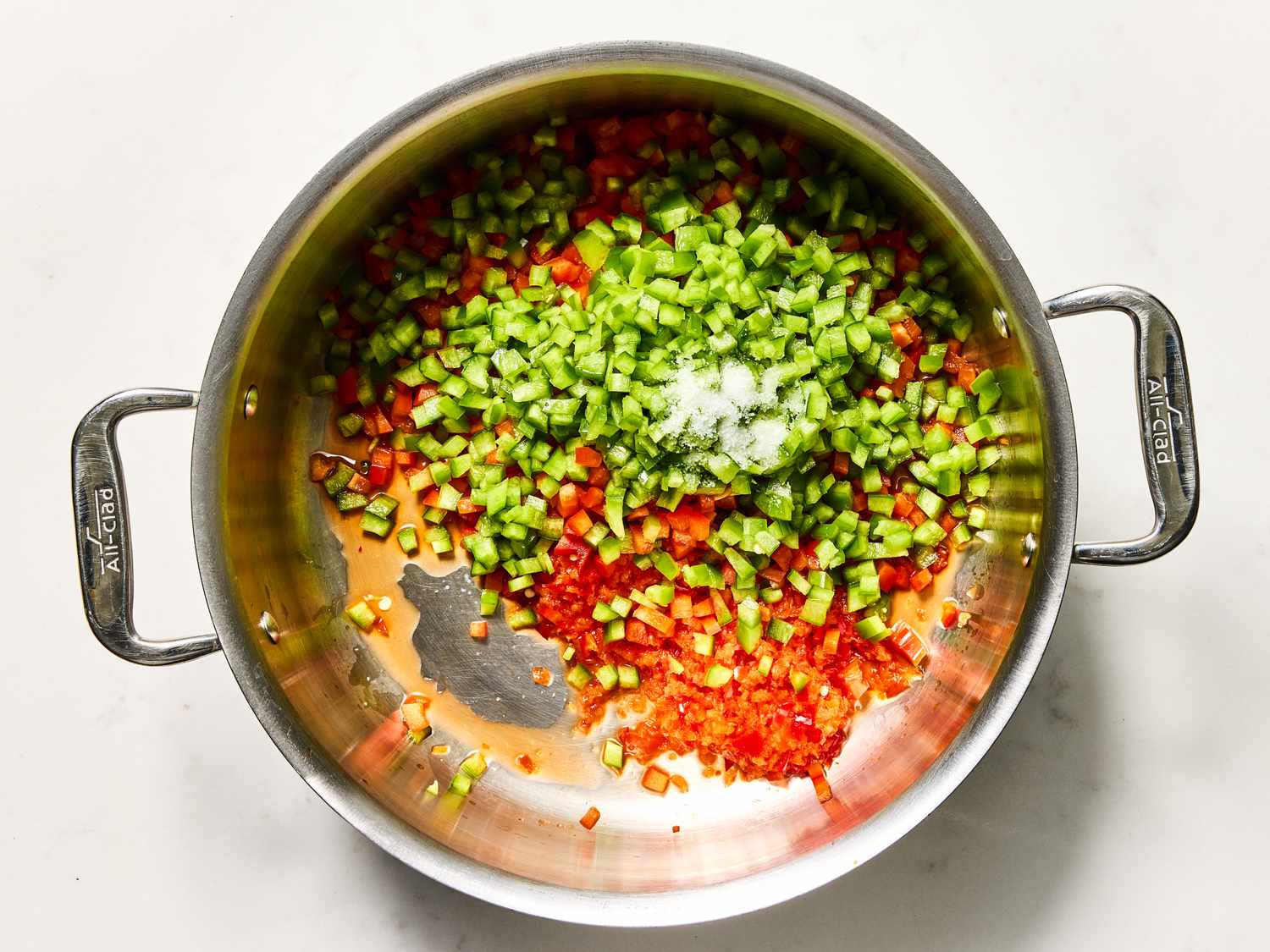 Chopped green and red peppers with salt in a metal pan