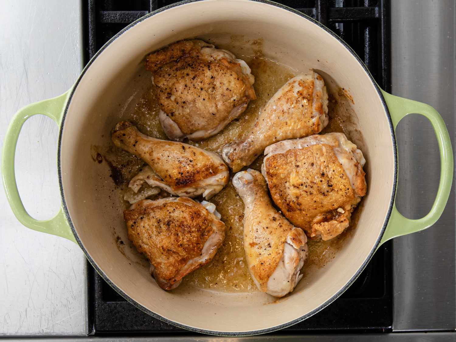 Six pieces of chicken (drumsticks and thighs) browned in a Dutch oven on a stove top