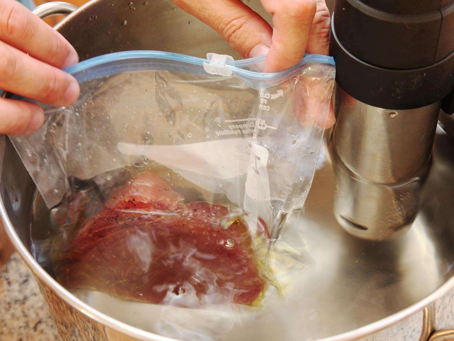 Bag containing seasoned tuna is being submerged in order to seal it with the displacement method.