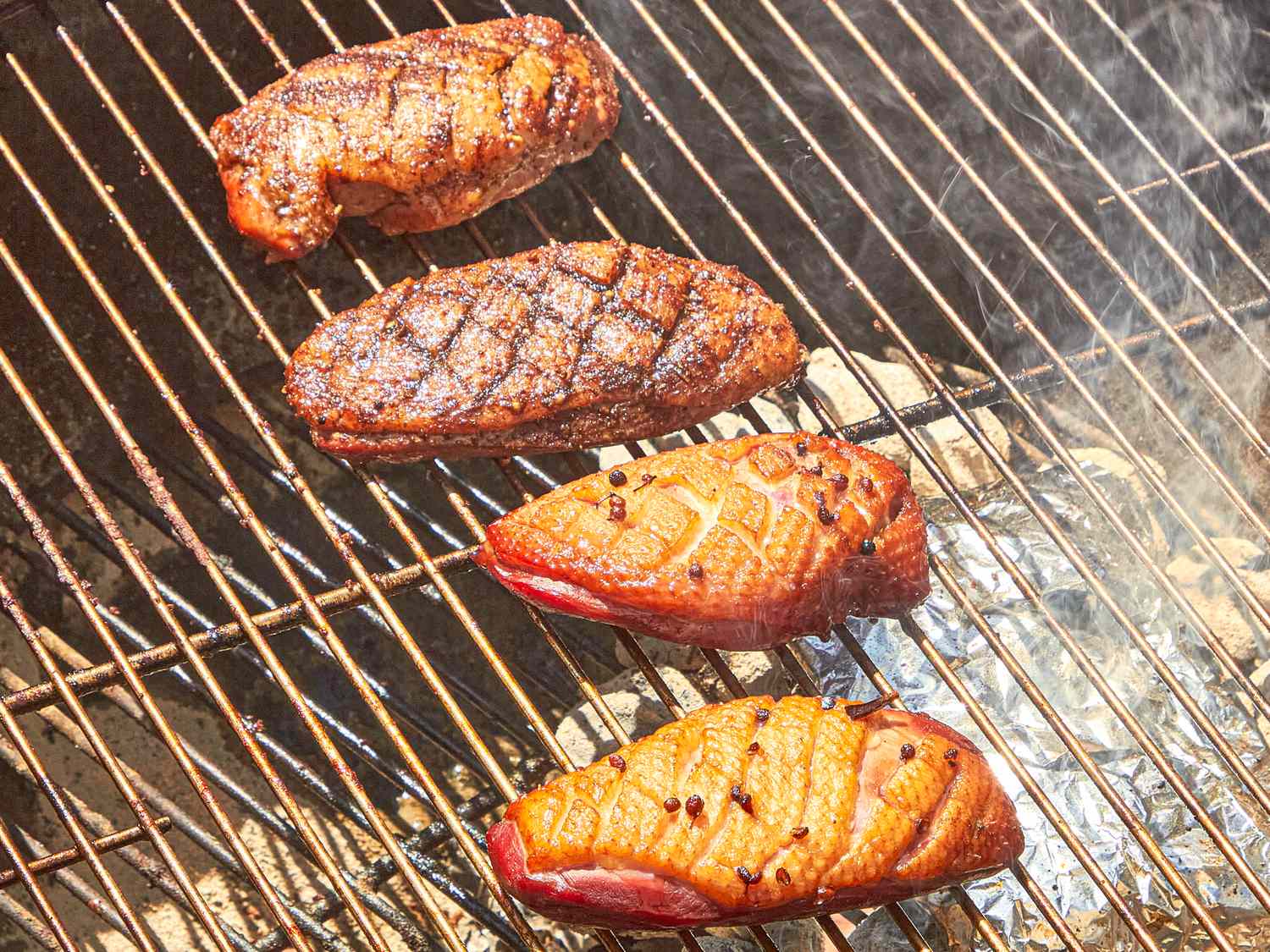 Grilled duck breasts being smoked on a barbecue grates
