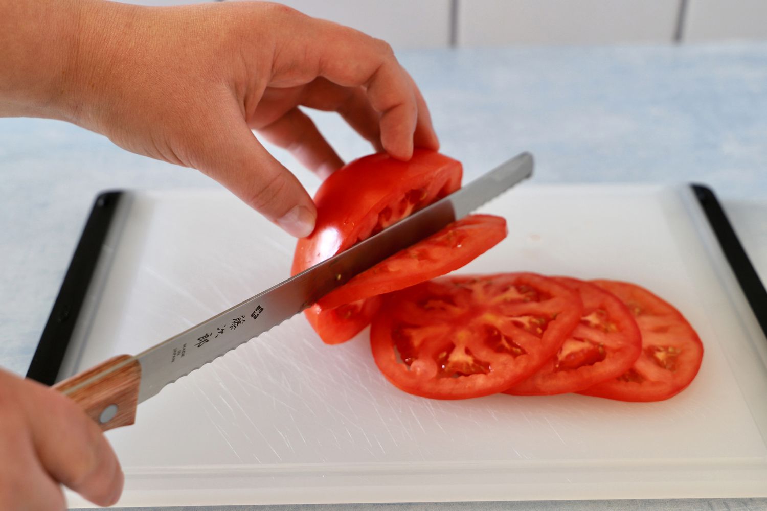 Person slicing tomatoes with Tojiro F-737 Bread Slicer