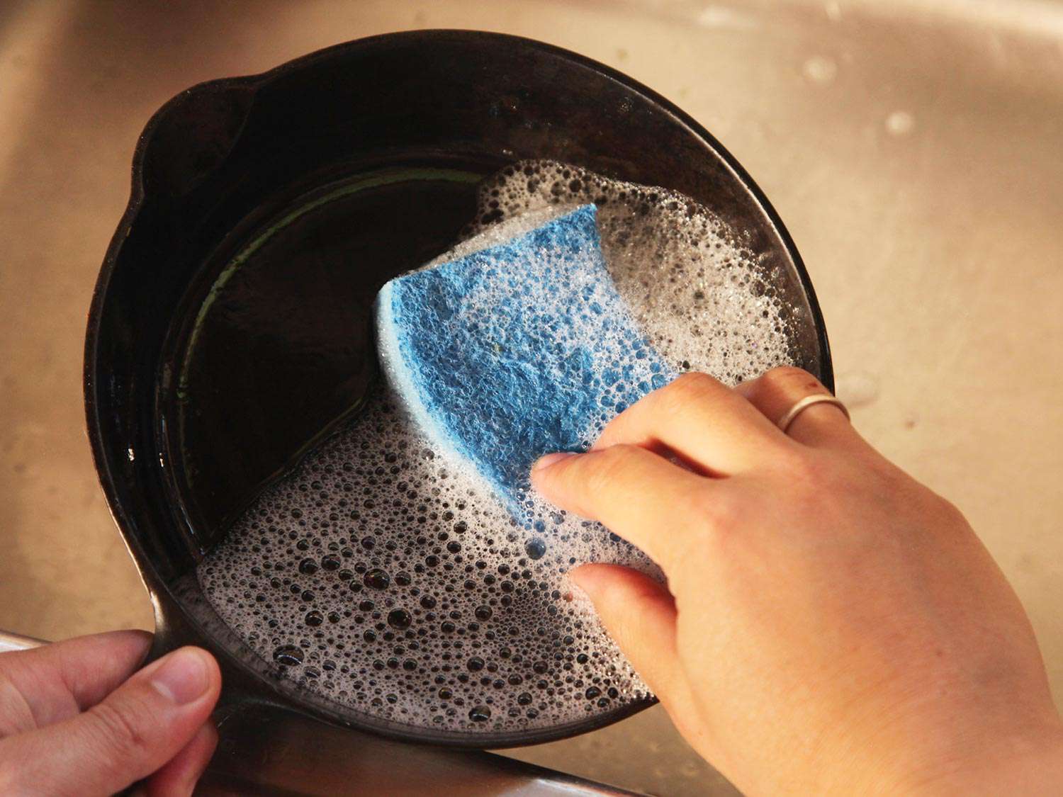 Washing cast iron skillet with sponge and soapy water