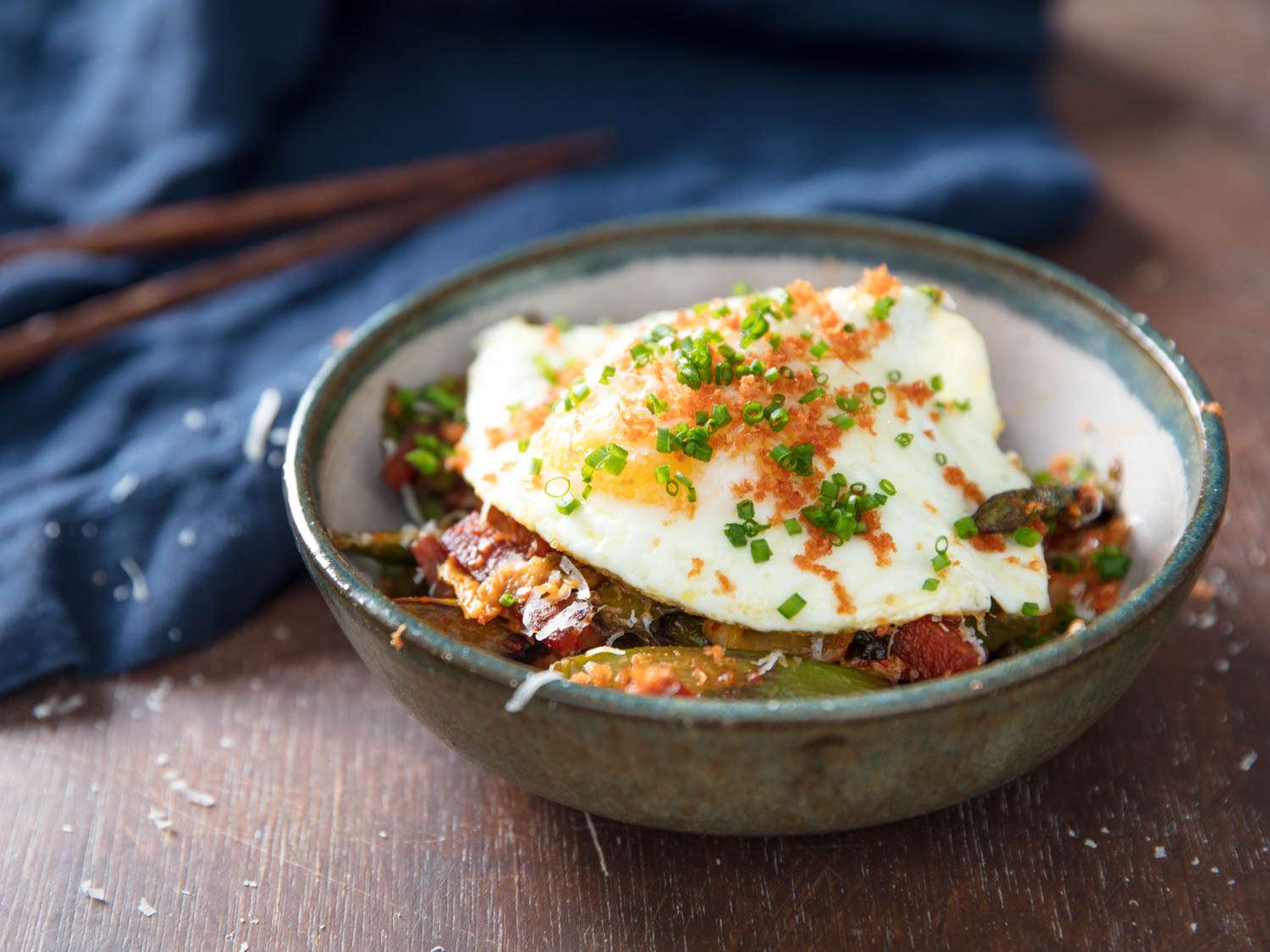 Kimchi and asparagus stir-fry with Spam and Fried egg served in a bowl and topped with grated Spanish chorizo and minced chive.