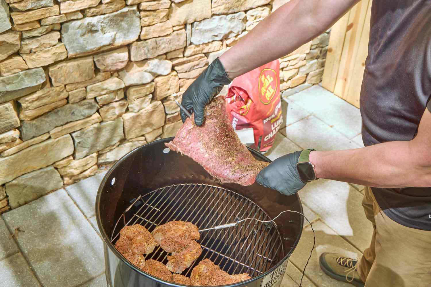 A person cooks meat in the Pit Barrel Cooker Co. Classic Pit Barrel Cooker