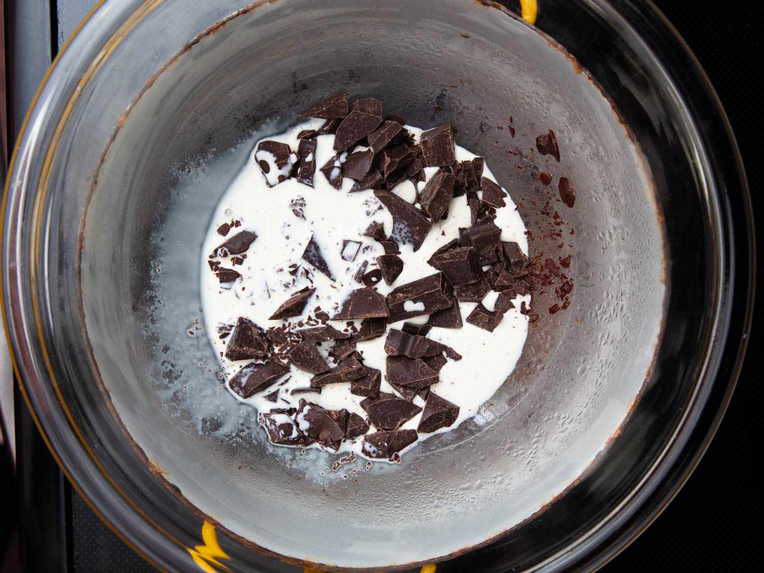 Chunks of chocolate being melted in milk. 