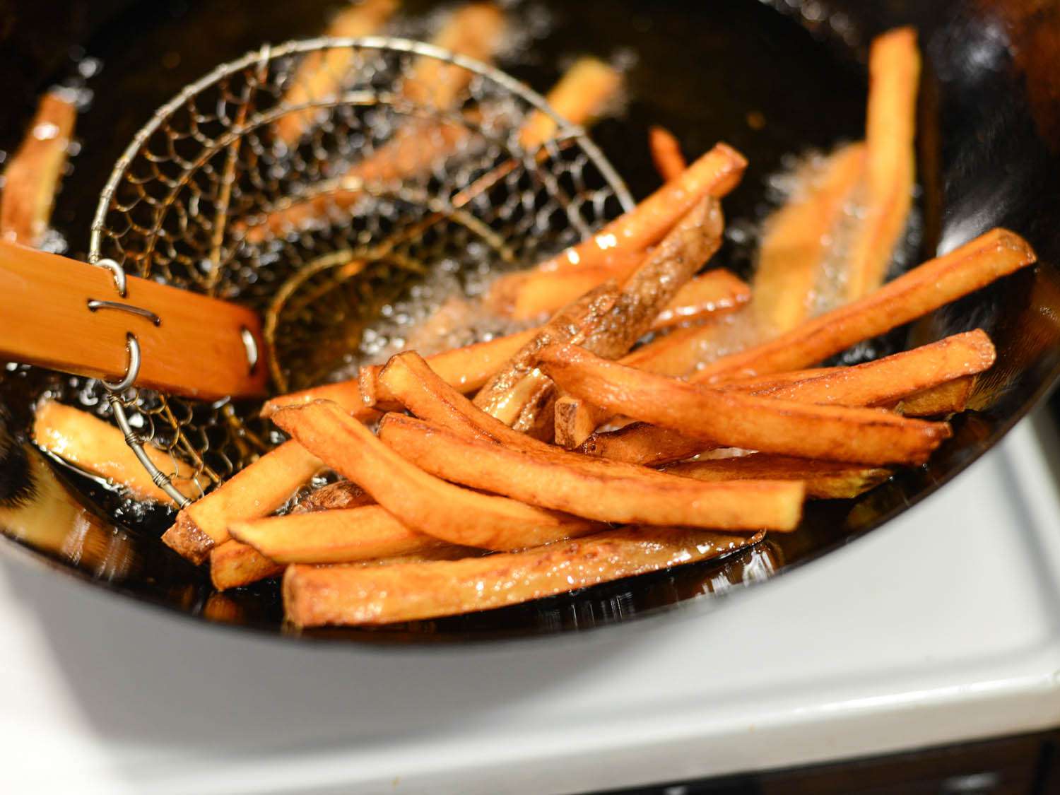 Fishing out fries from the frying pan with a spider.