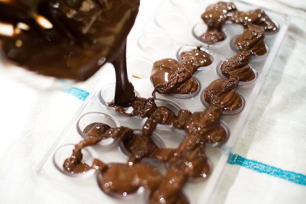Filling the bonbon molds with melted, tempered chocolate.