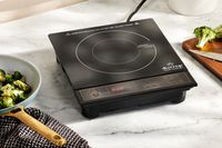 Duxtop BT-180G3 1800W Portable Induction Cooktop Countertop Burner next to cooked broccoli on a table