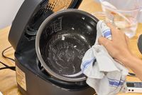 A person lifts the bowl from the Zojirushi NW-QAC10 Induction Heating Rice Cooker & Warmer