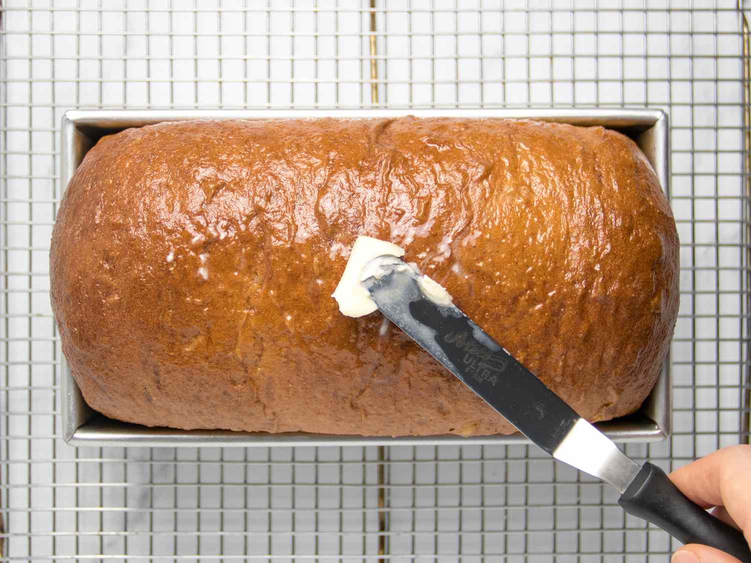 Spreading butter onto baked loaf 