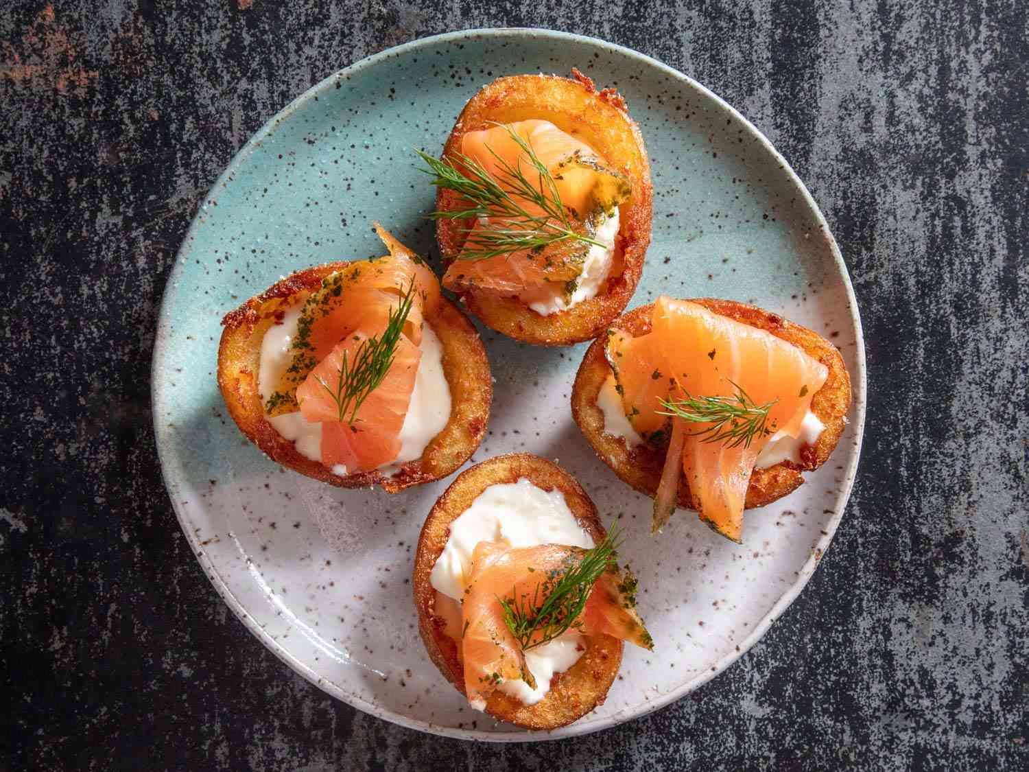 Deep-fried potato skin cups filled with thick and tangy crème fraiche and topped with smoked salmon and dill sprigs