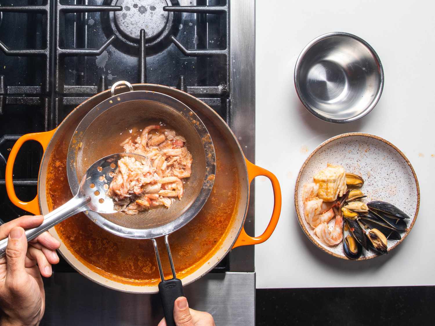 Adding the warmed crabmeat to the serving plates.