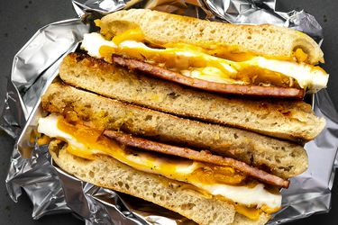 A cooked homemade Egg McMuffin, split in half and wrapped in aluminum foil.