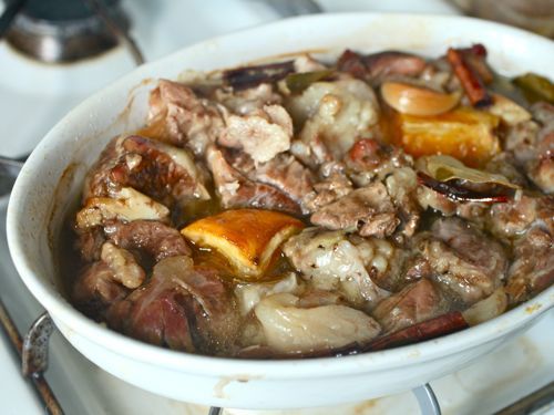 Baking dish with pork shoulder, spices, and oranges for carnitas.