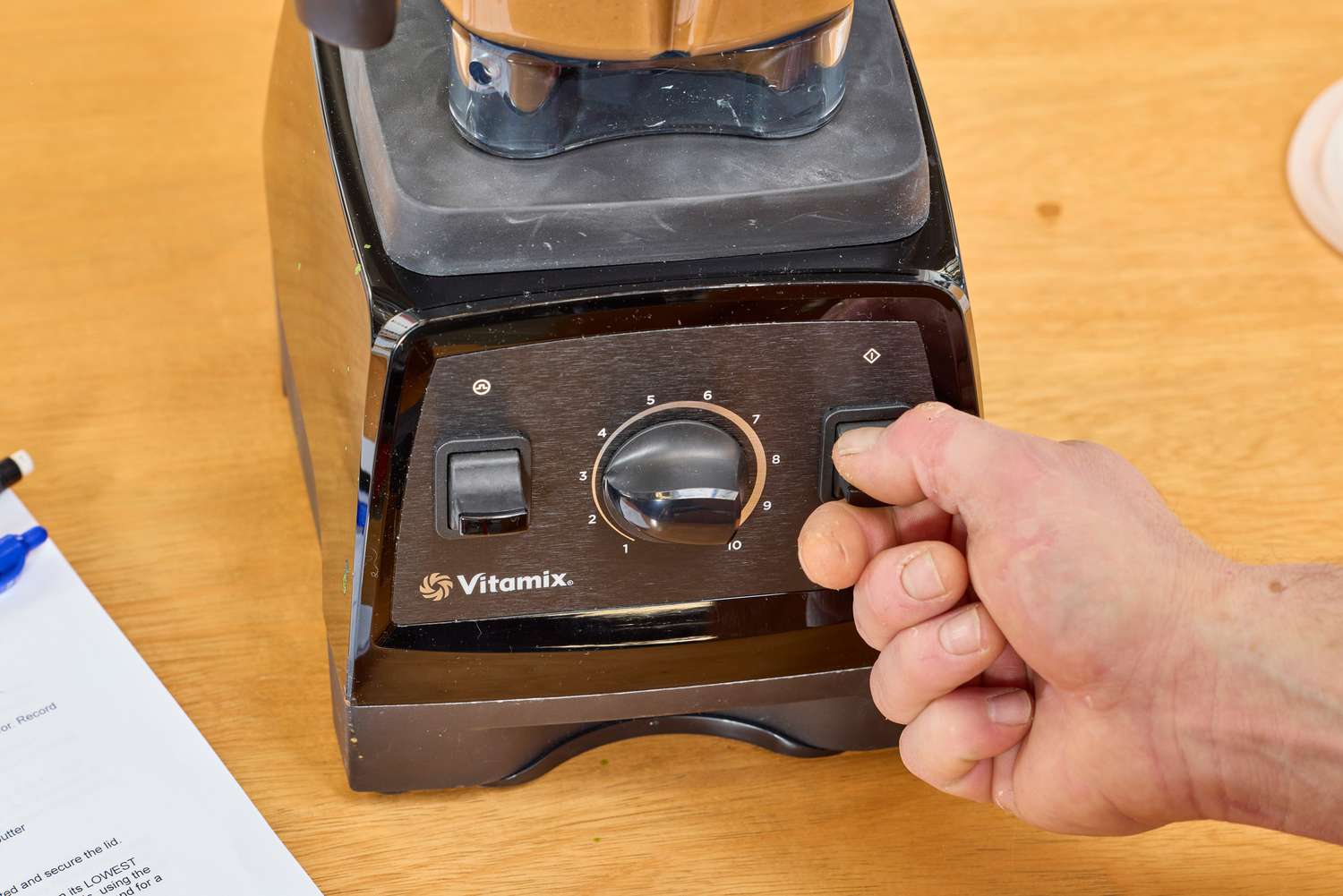 A close-up of a hand flipping a switch on the Vitamix 7500