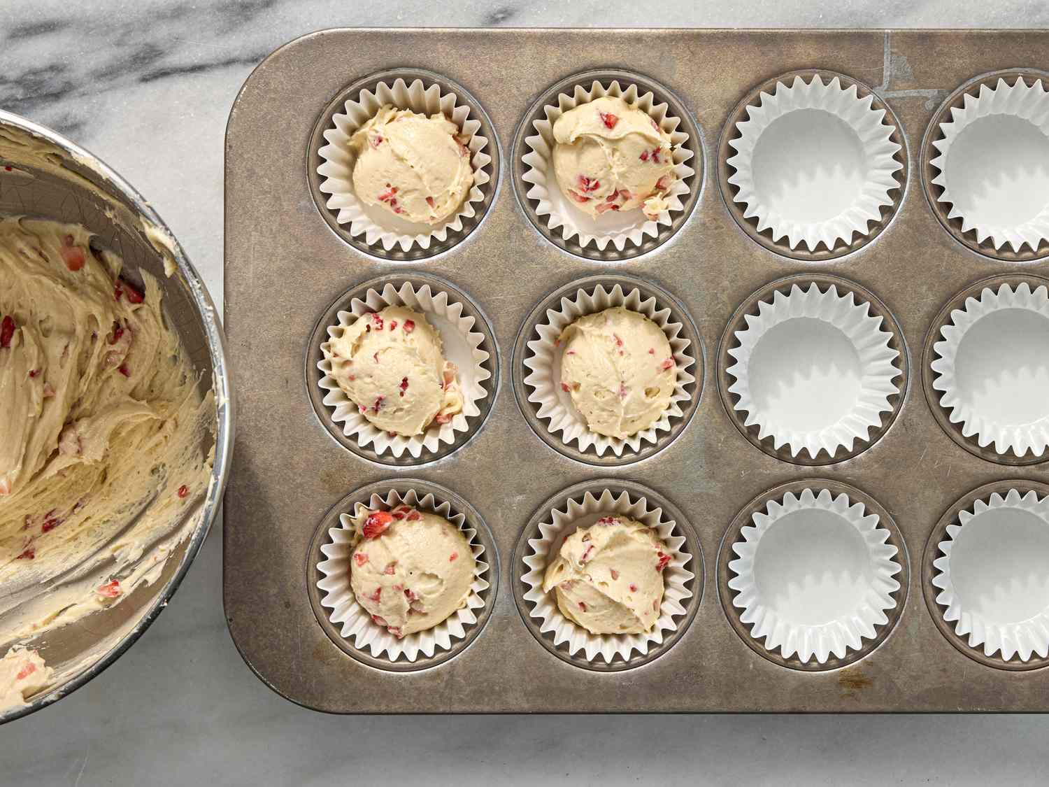 putting cupcake batter in tins lined with muffin paper 