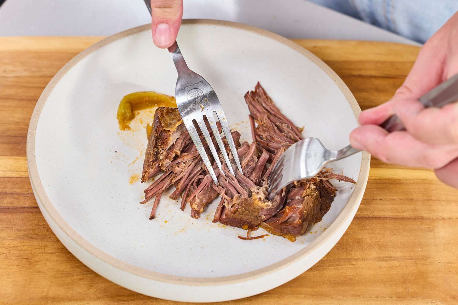 A person shreds meat cooked in the T-Fal Clipso Pressure Cooker using two forks