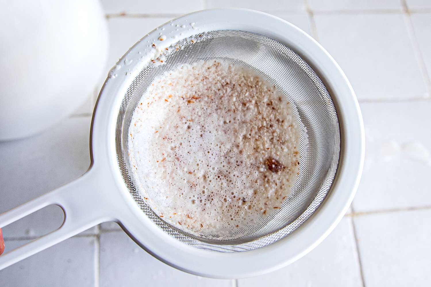 straining nut pulp through a sieve