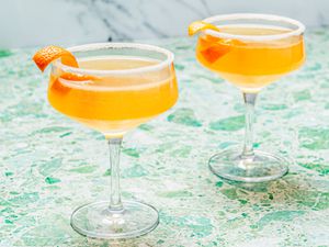 Two sidecar cocktails in stemmed cocktail glasses with sugared rims and an orange peel garnish 