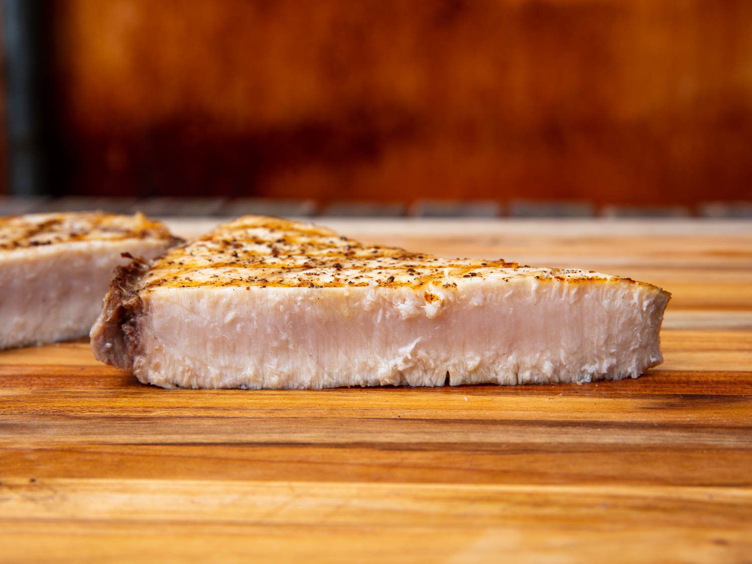 A cross-section of a piece of grilled swordfish steak showing the ideal doneness level: it still has a trace of translucence in the center.