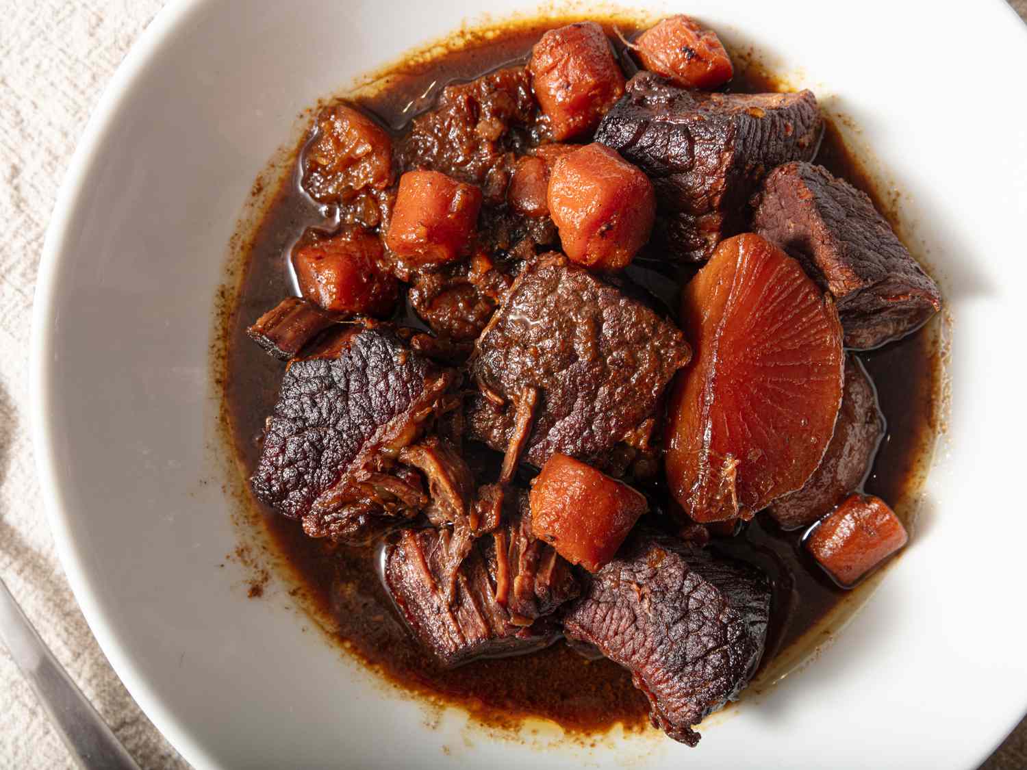white dish of Cantonese braised brisket on a white tablecloth