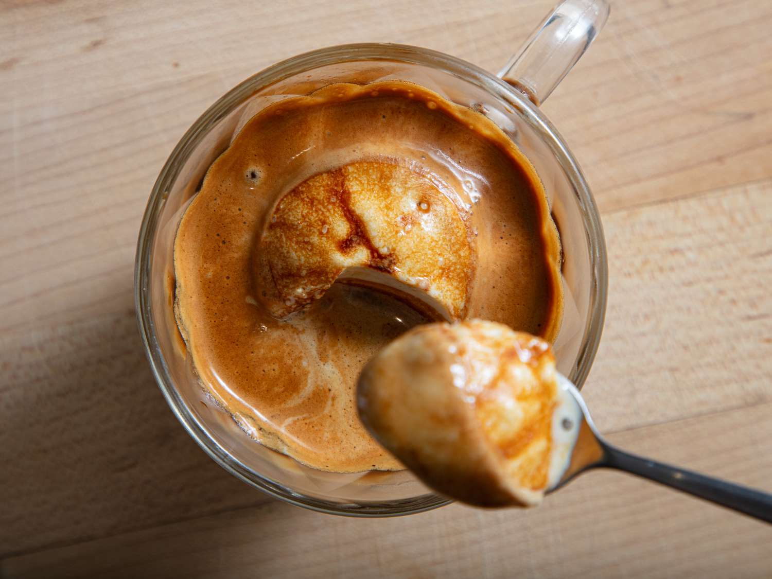 A glass cup containing an affogato dessert with espresso poured over a scoop of ice cream