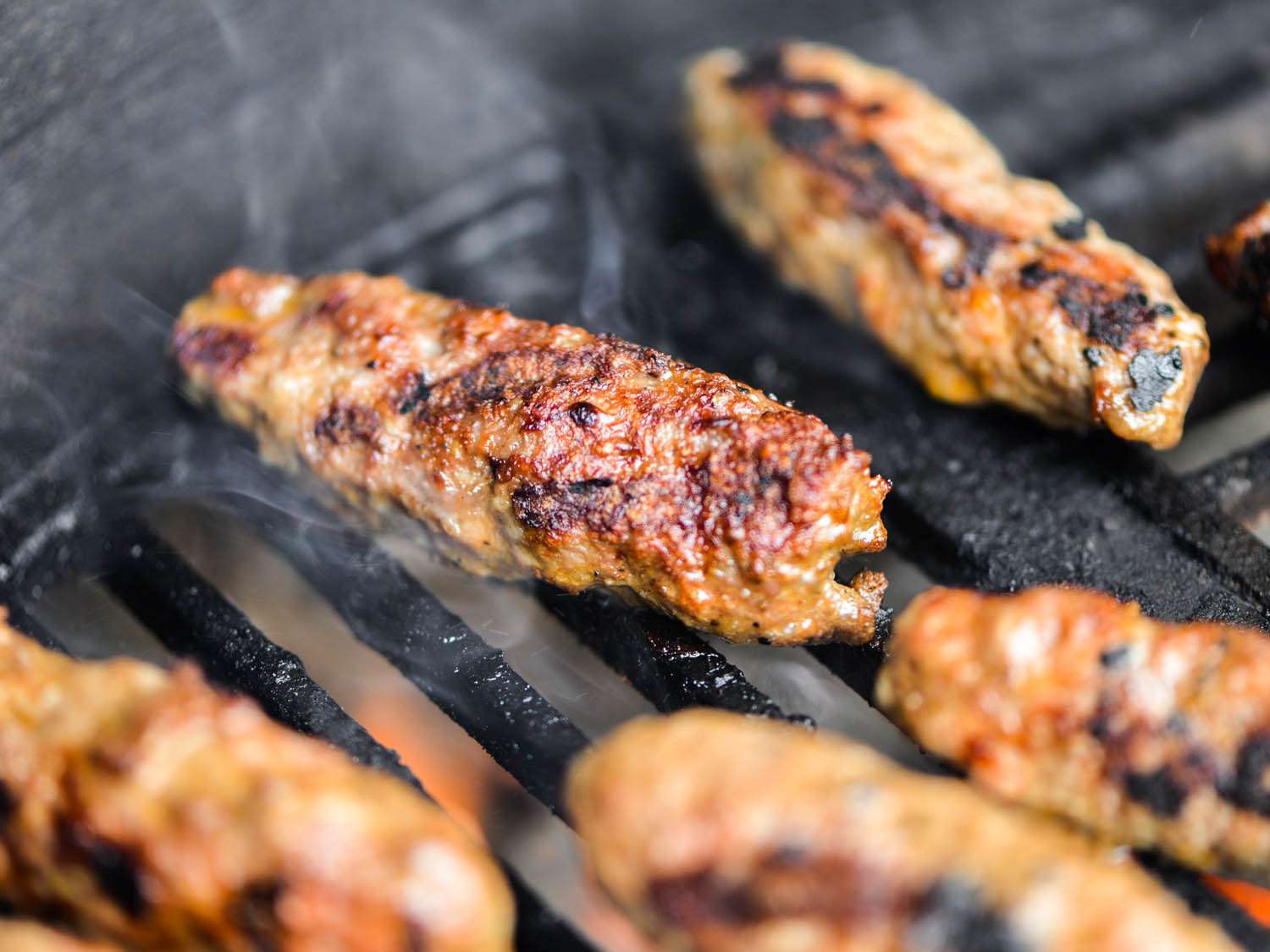 Close up of browned sheftalia sausages on a grill grate.