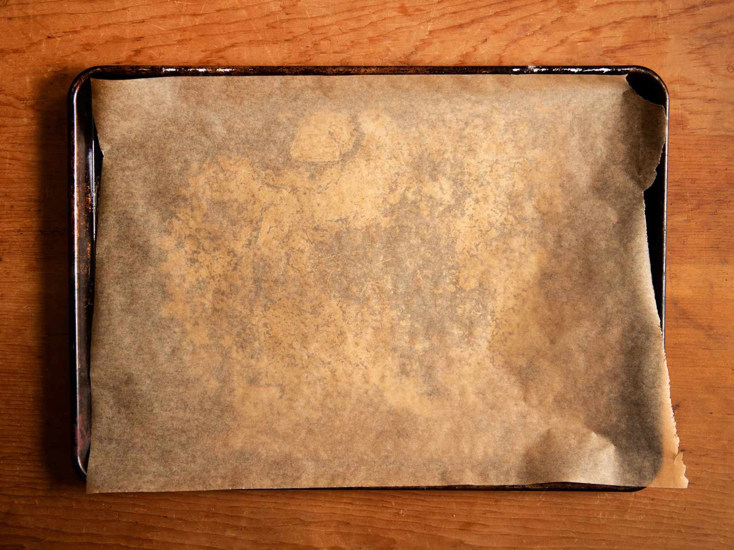 A rimmed baking sheet lined with parchment paper on a wood counter.