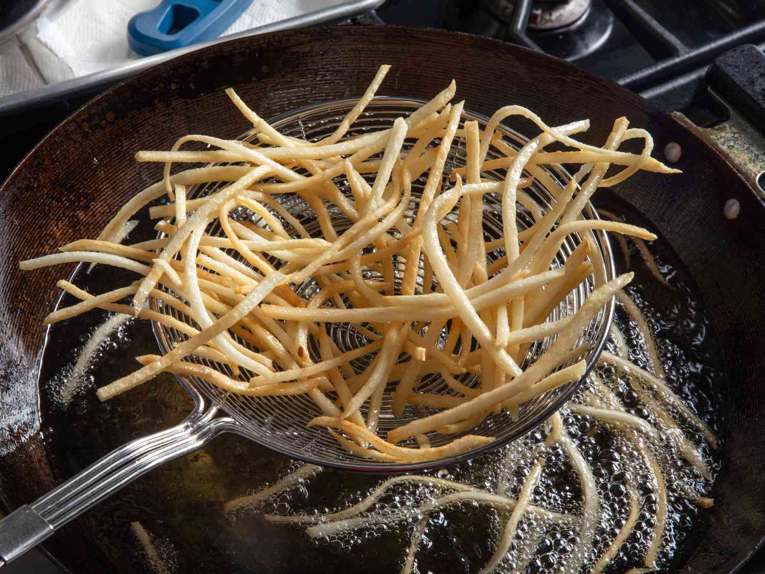 Shoestring fries in a spider strainer after second fry