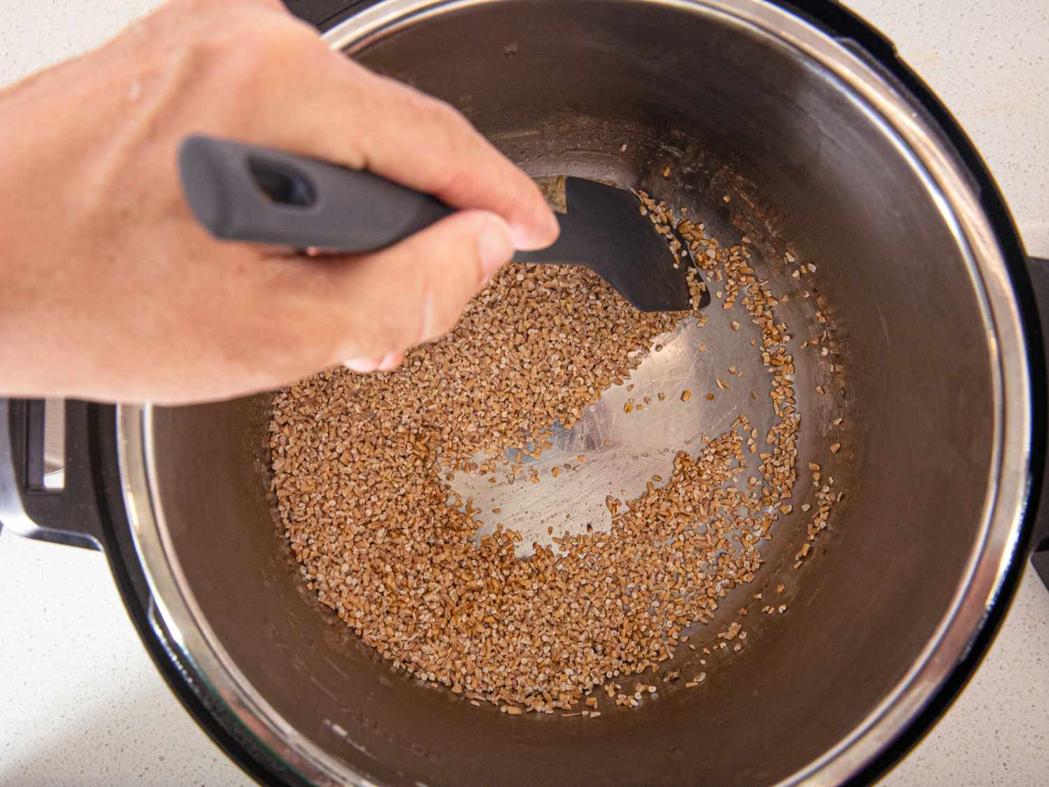 Overhead view of toasting oats with butter in a pressure cooker