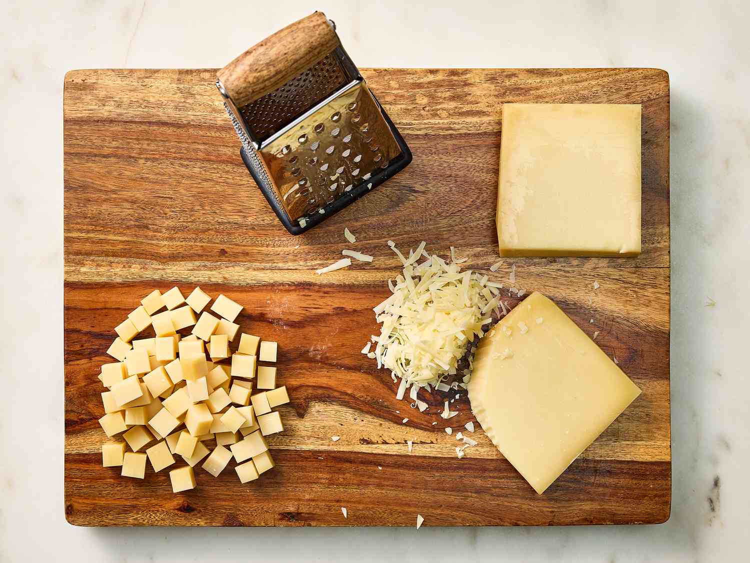 Shredded cheeses on a wooden board and a cheese grater 
