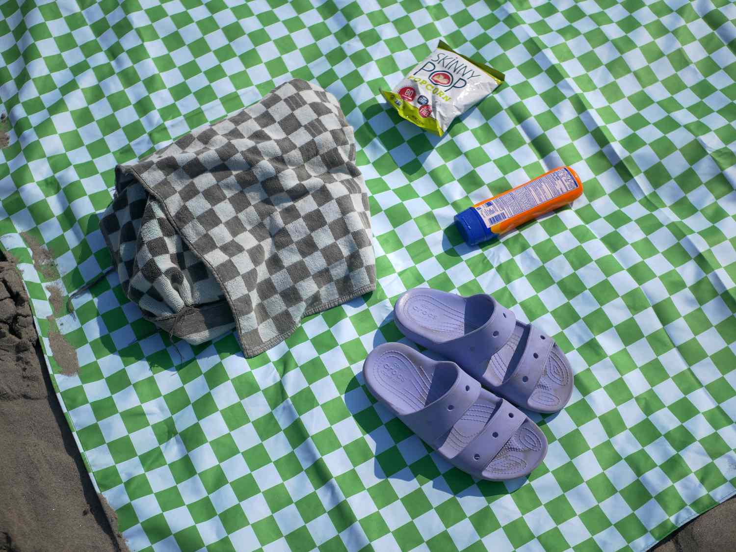 overhead view of nomadix blanket with towel, popcorn, sunscreen, and shoes
