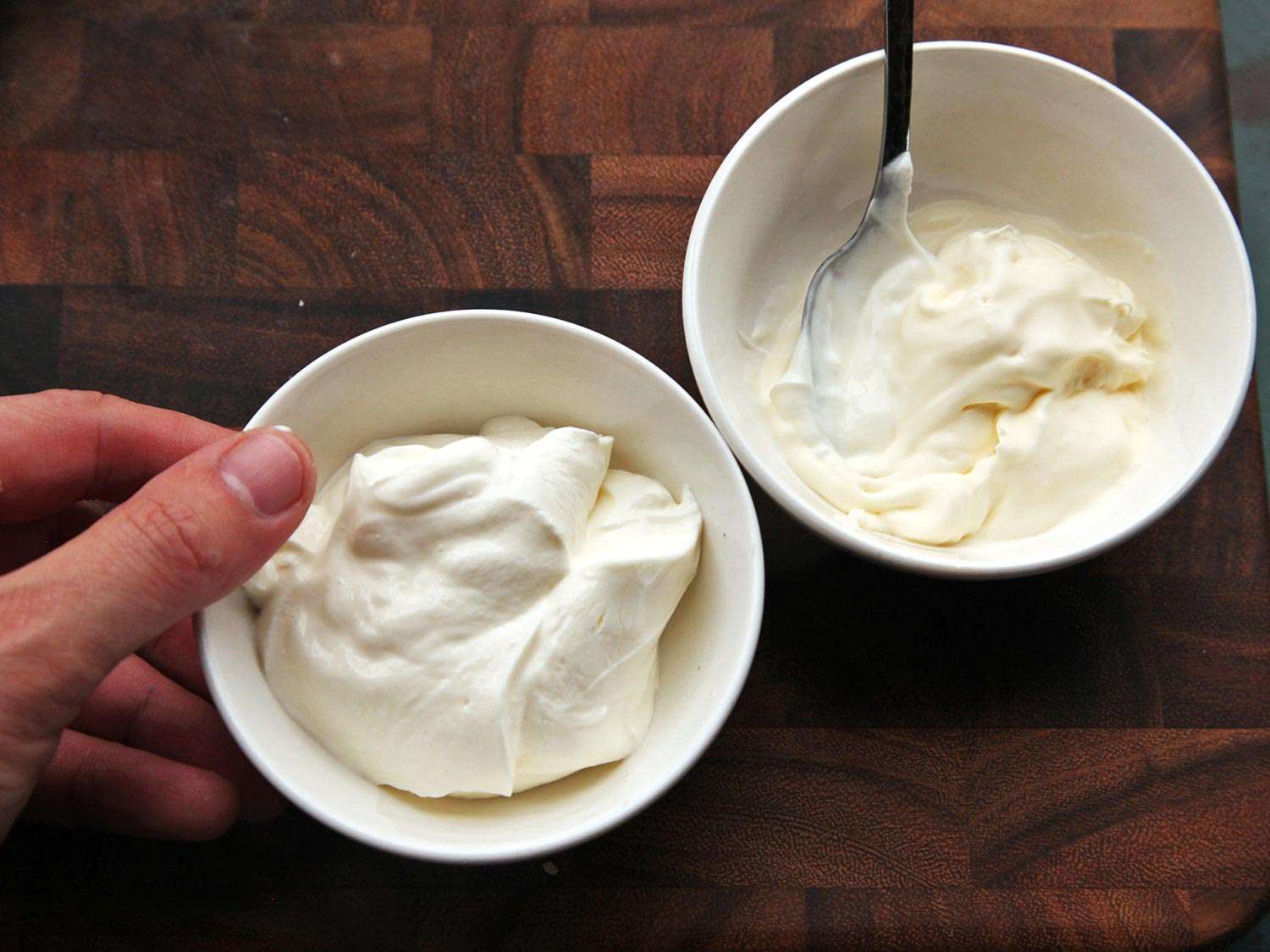 Two small bowls holding scoops of sour cream.