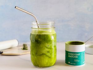 A glass of Rishi Tea Everyday Matcha next to the container