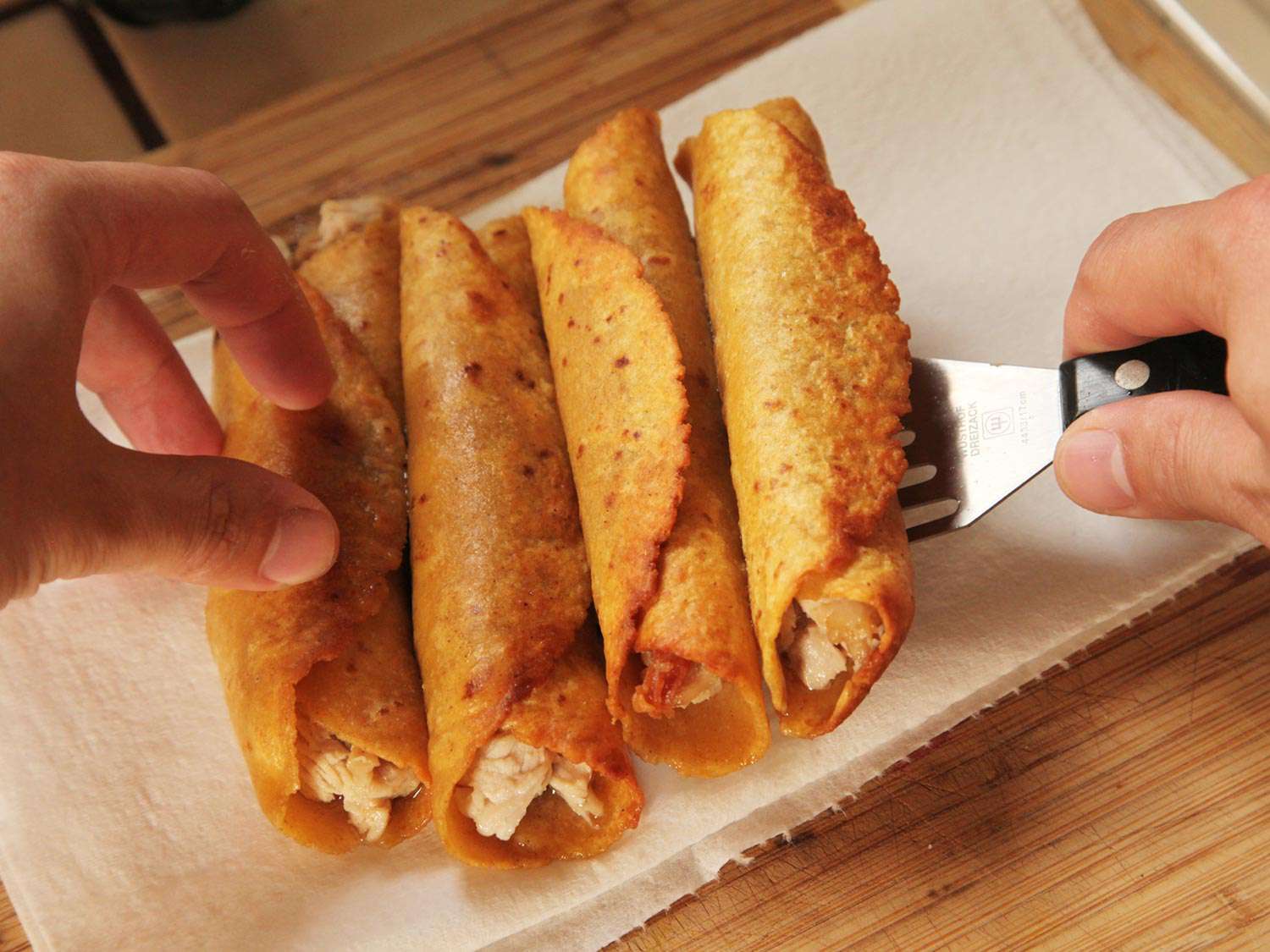 Transferring a batch of turkey enchilada to a paper towel with a fish turner. 