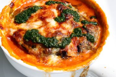 Closeup of eggplant tian, dolloped with pistou.