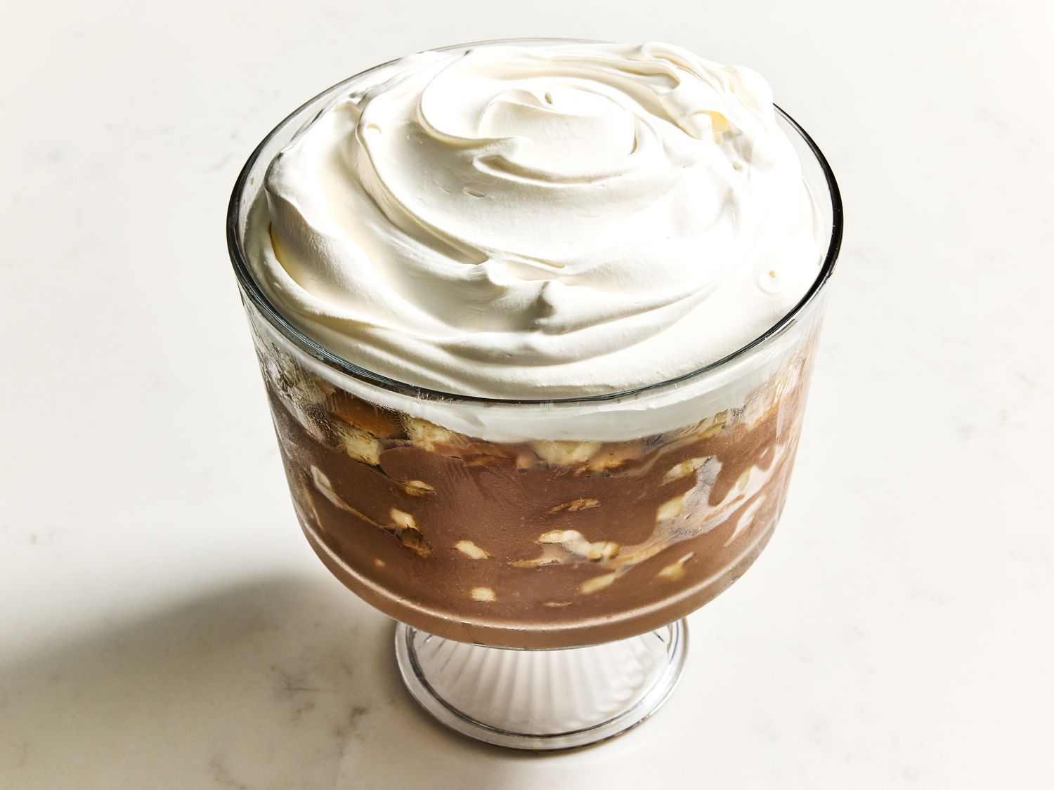 Layered chocolate banana pudding in a trifle bowl topped with whipped cream