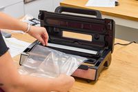 A person creates a plastic bag from the Nesco VS-12 Deluxe Vacuum Sealer