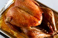 Roasted turkey resting on a rack over a baking tray