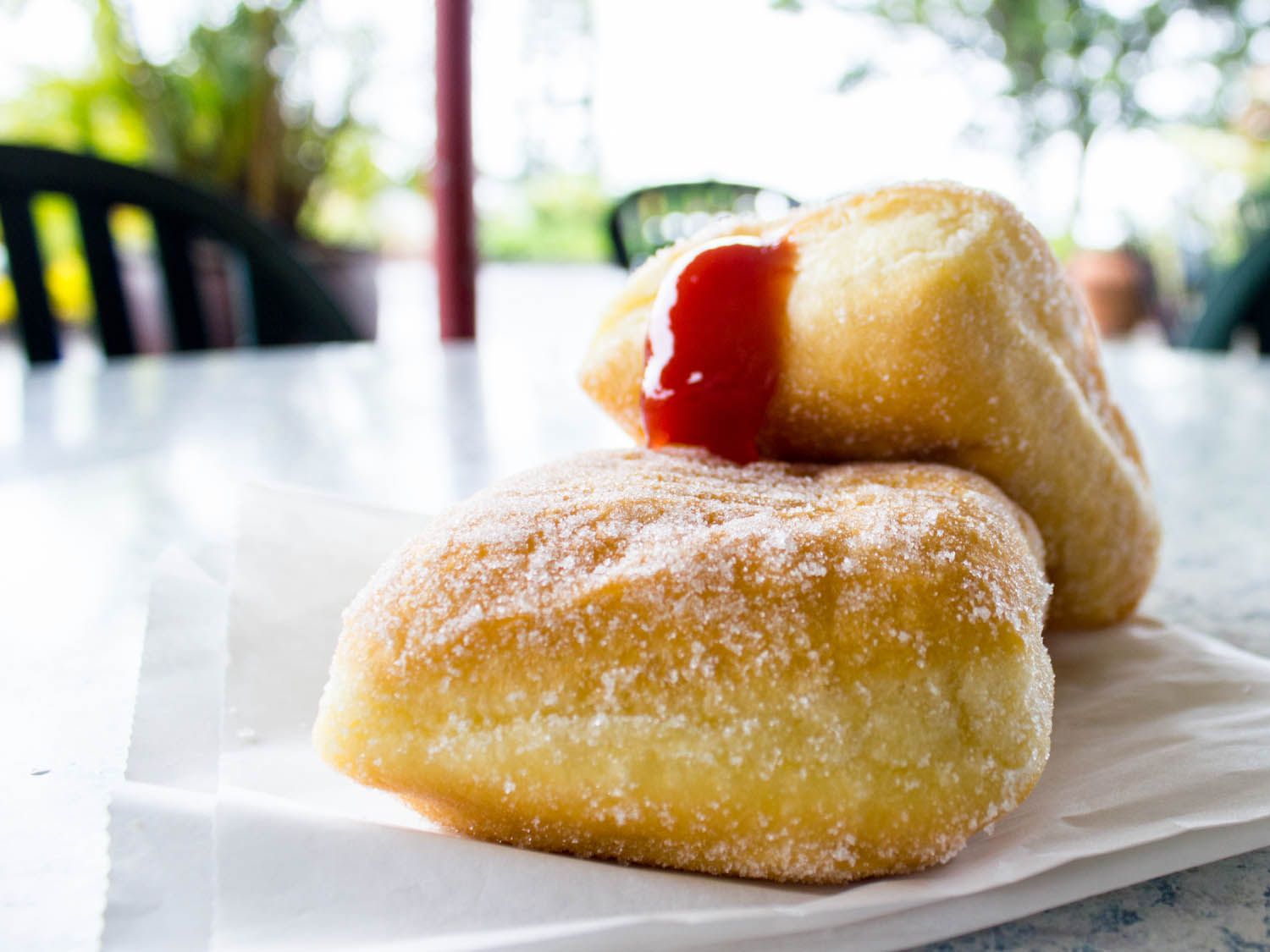 Two malasadas resting on a paper bag.